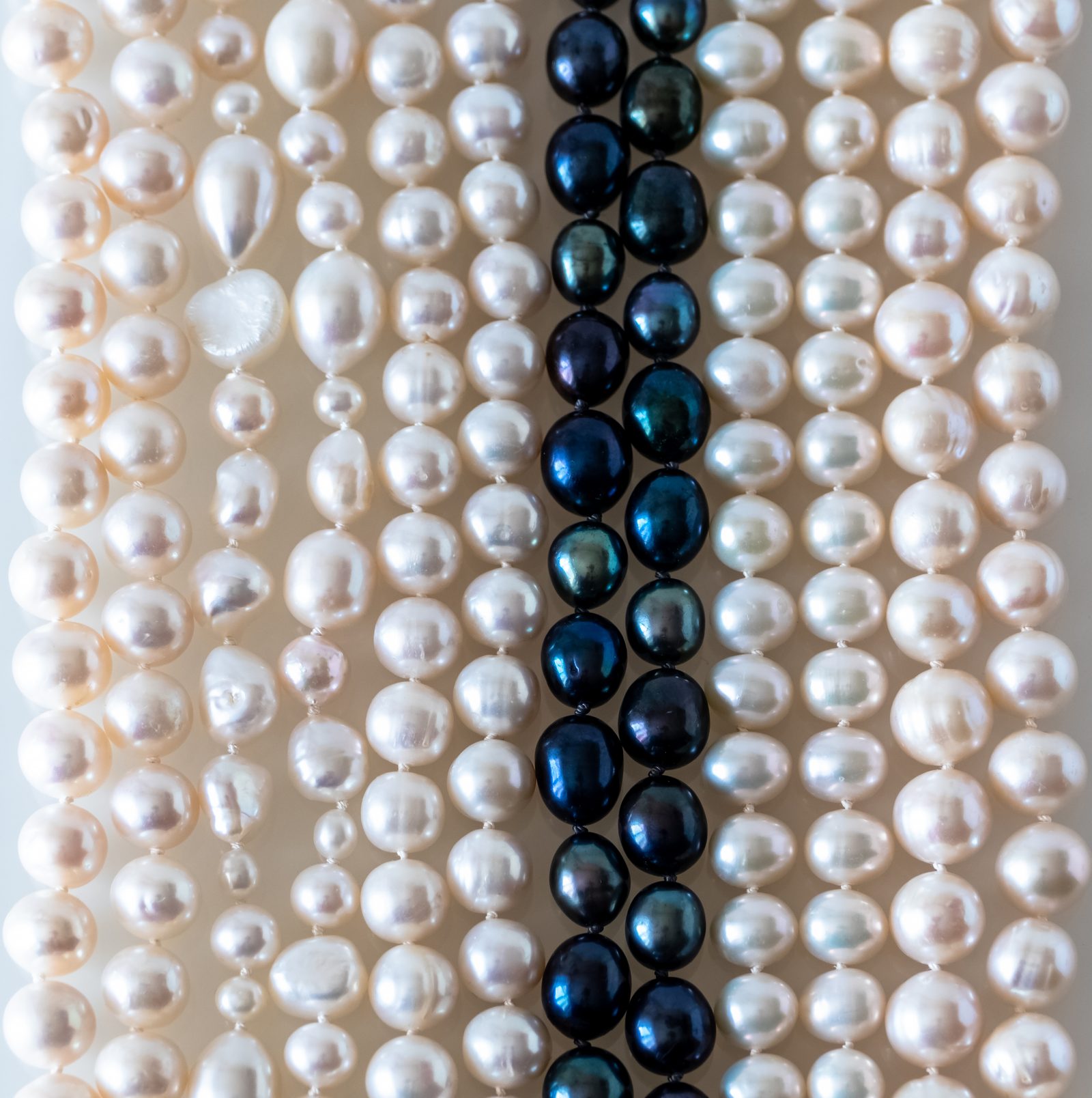 Strands of natural white, round, and dyed-blue freshwater pearls threaded on silk