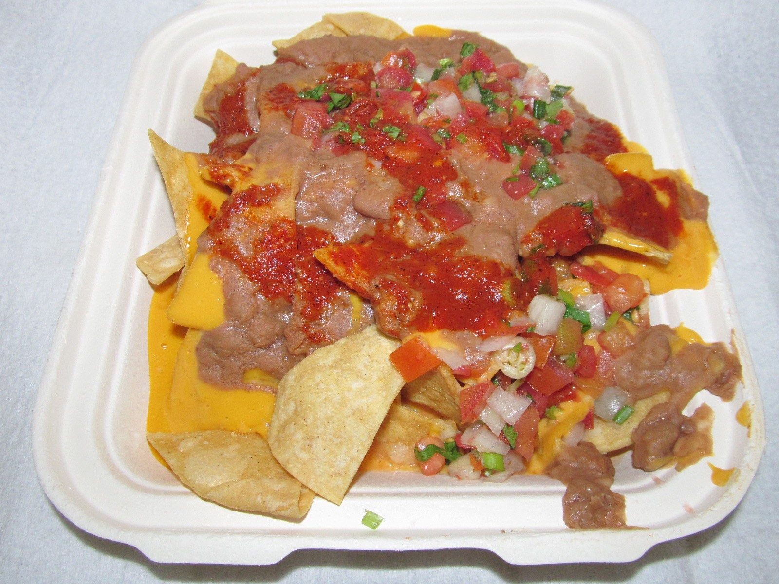 A large platter of loaded nachos topped with melted cheese, jalapeños, and salsa